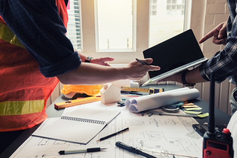 Two construction workers utilizing a laptop for real-time asset management with the help of a software module.