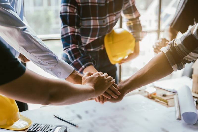 A group of construction workers shaking hands after completing a successful facility inspection using realtime software.