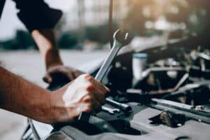 Car mechanic is holding a wrench ready to check the engine and maintenance.