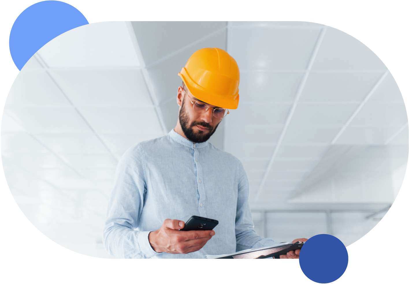 A man wearing a hard hat in a facility rentals site, holding a cell phone.