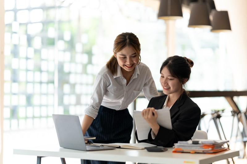 Two business women using a lock manager module to collaborate on a laptop in an office.