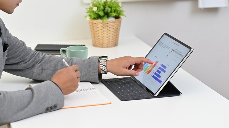 A businessman is using a realtime software on an iPad to manage timesheets.