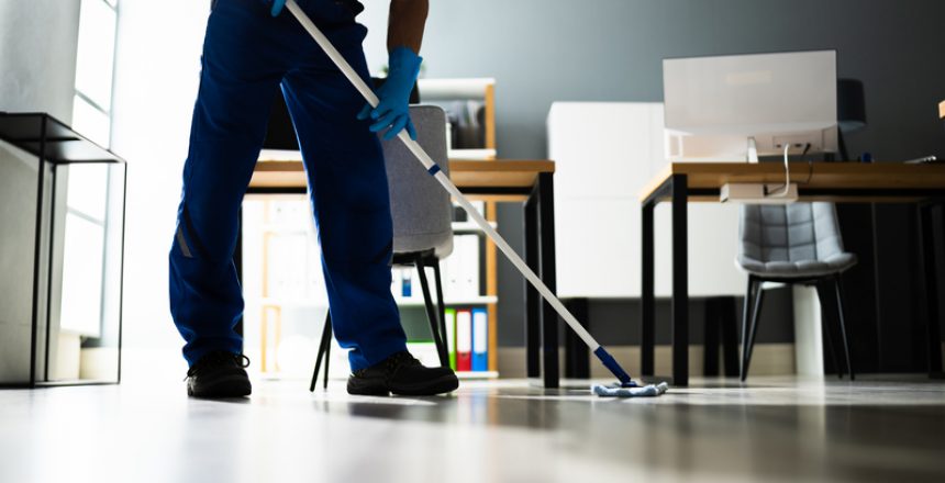 Male Janitor Mopping Floor In Face Mask In Office