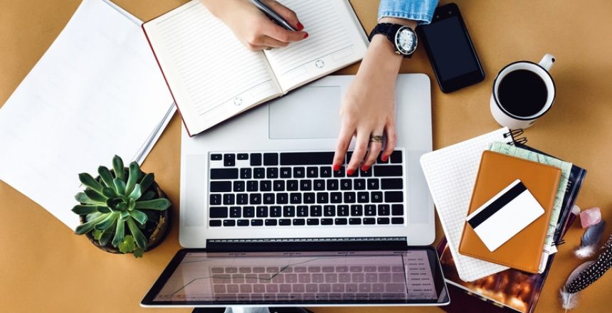 A woman multitasking with Registrations Module software, typing on a laptop alongside a cup of coffee.