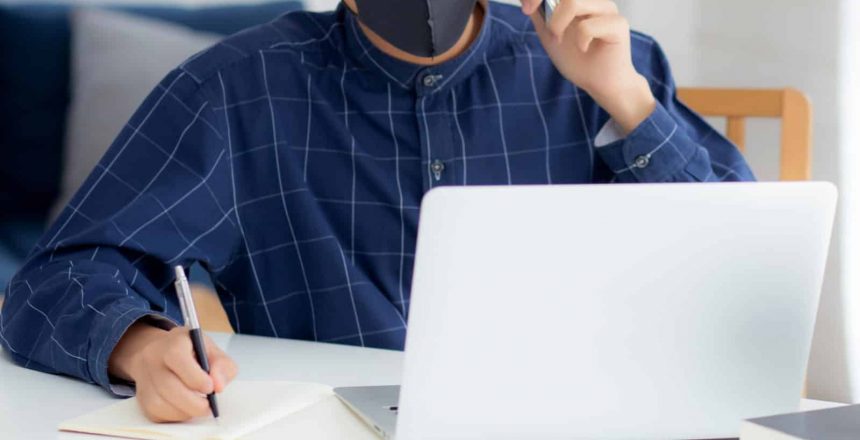 A man utilizing a face mask while effectively working on a laptop, enhancing productivity with module upgrades.